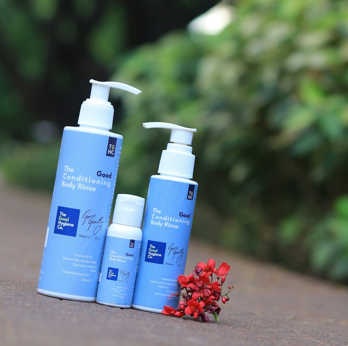 Three blue bottles of conditioning body lotion outdoors.